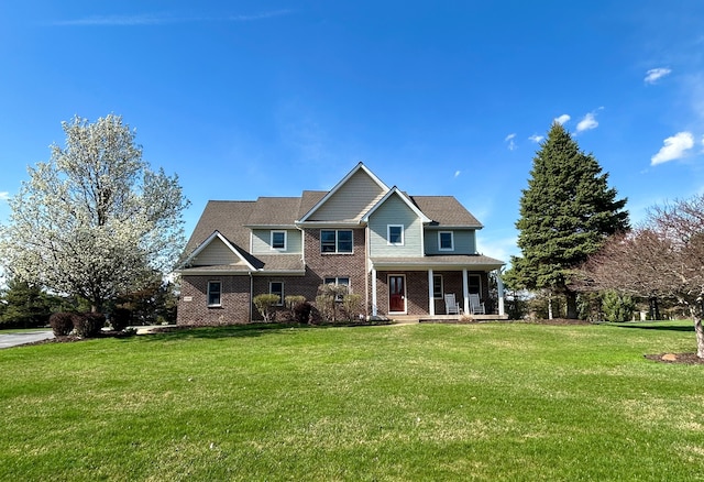 view of front of property featuring a porch, a front lawn, and brick siding