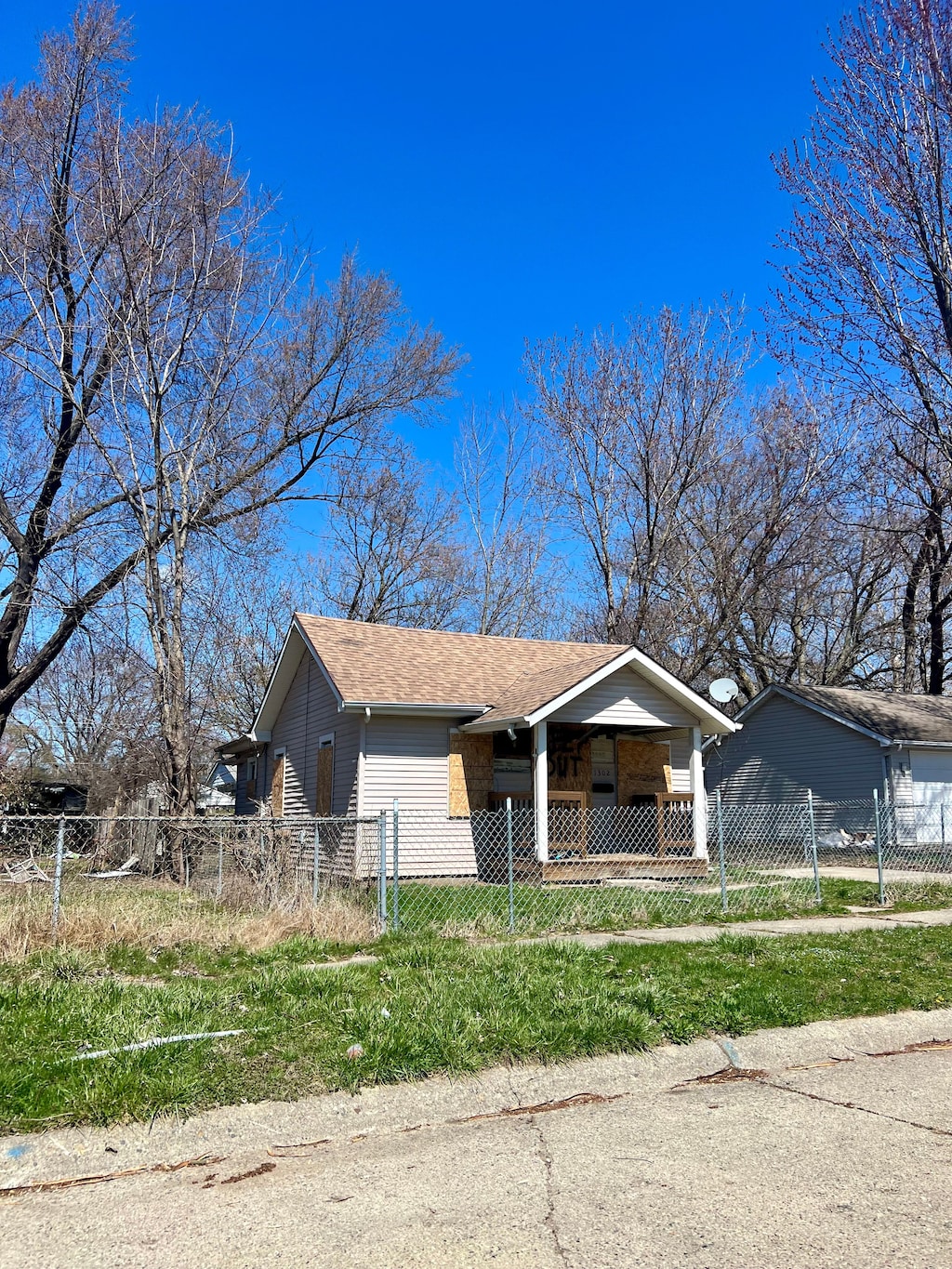 bungalow with a shingled roof, a fenced front yard, and a porch