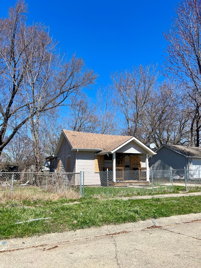 bungalow with a shingled roof, a fenced front yard, and a porch