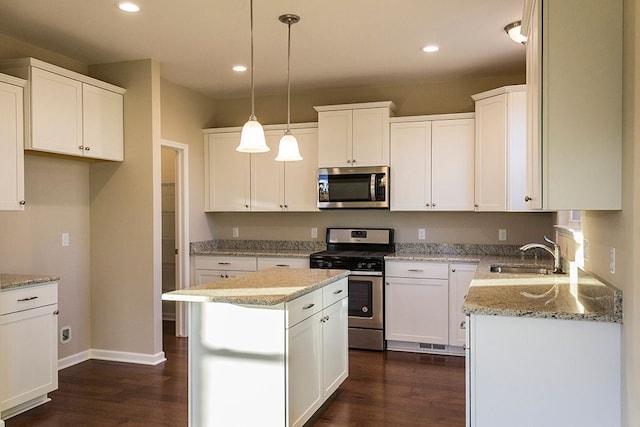 kitchen with dark wood finished floors, appliances with stainless steel finishes, white cabinets, and a sink