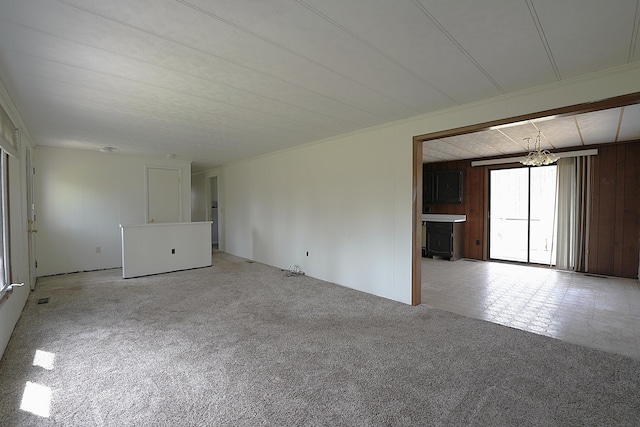 carpeted empty room featuring a wood stove and a notable chandelier