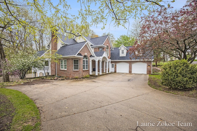 view of front facade with a chimney, brick siding, an attached garage, a shingled roof, and concrete driveway