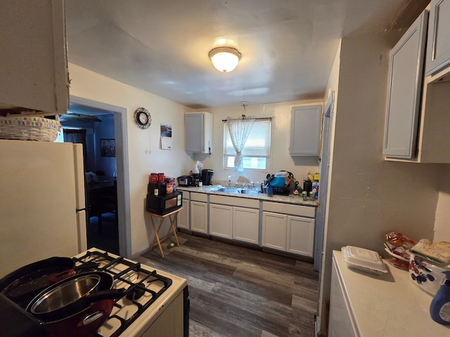 kitchen featuring white appliances, light countertops, a sink, and dark wood-type flooring