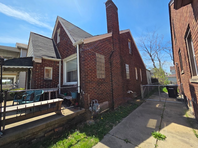 view of home's exterior with a chimney, cooling unit, and brick siding