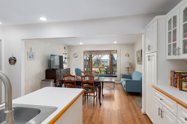 3928 Embarcadero St, Waterford, MI 48329 - kitchen with light wood-style flooring, a sink, white cabinetry, glass insert cabinets, and light countertops