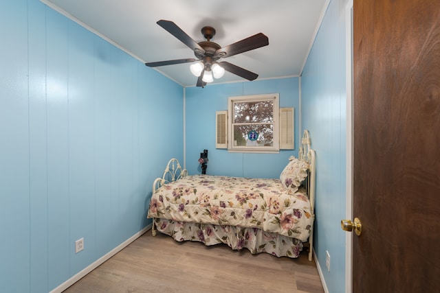bedroom with wood finished floors, ornamental molding, baseboards, and ceiling fan
