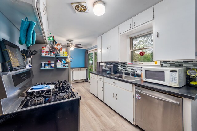 kitchen featuring stainless steel appliances, backsplash, a sink, and dark countertops