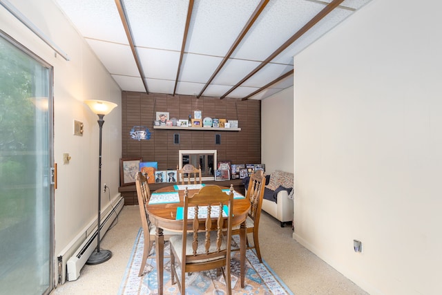 dining space with a baseboard heating unit, a drop ceiling, and baseboards