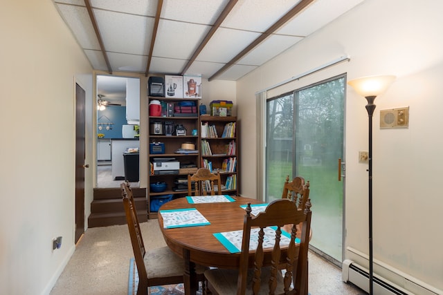 dining area featuring a baseboard heating unit, a drop ceiling, baseboards, speckled floor, and ceiling fan