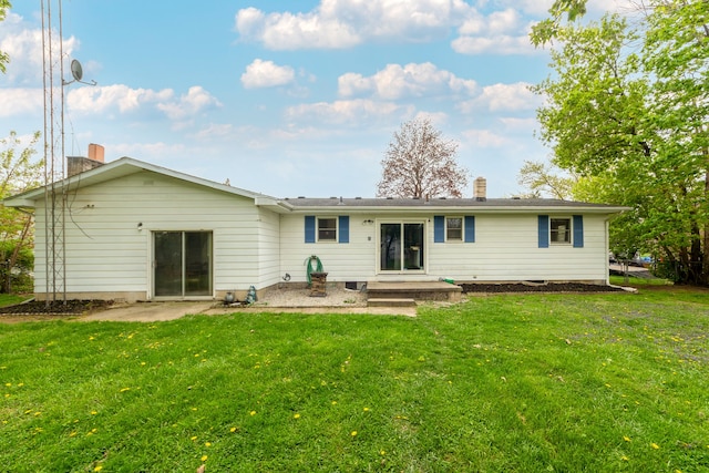 rear view of property with a chimney, a lawn, and a patio area