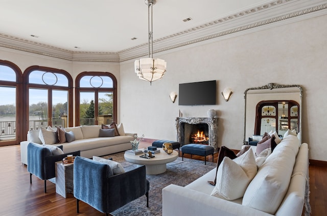living room with dark wood finished floors, a premium fireplace, crown molding, and a towering ceiling