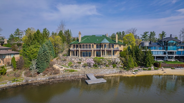 rear view of house with a chimney, a water view, and metal roof