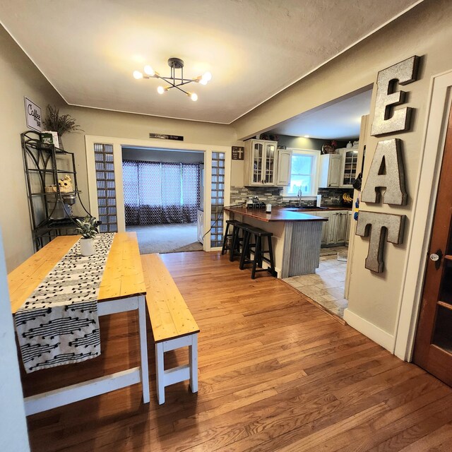 dining room with baseboards, light wood-style floors, and an inviting chandelier