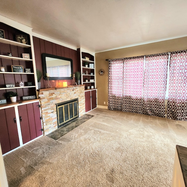 unfurnished living room with ornamental molding, carpet, and a stone fireplace