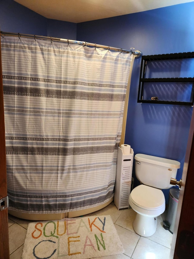 bathroom featuring tile patterned flooring, toilet, and a shower with curtain