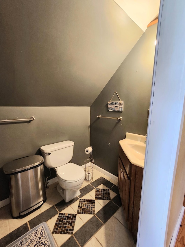 half bath featuring tile patterned floors, toilet, lofted ceiling, and vanity