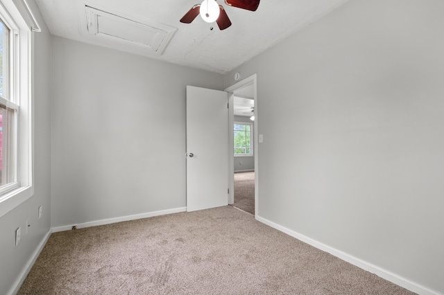 unfurnished room featuring baseboards, carpet flooring, attic access, and ceiling fan