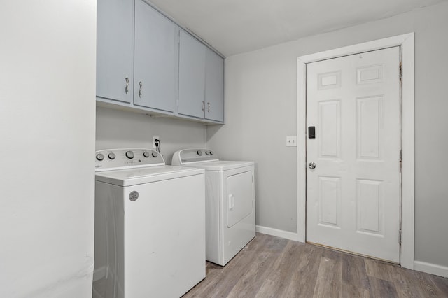 laundry room featuring light wood finished floors, cabinet space, baseboards, and washer and dryer