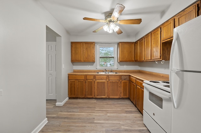 kitchen featuring light wood-style flooring, brown cabinetry, white appliances, a sink, and light countertops