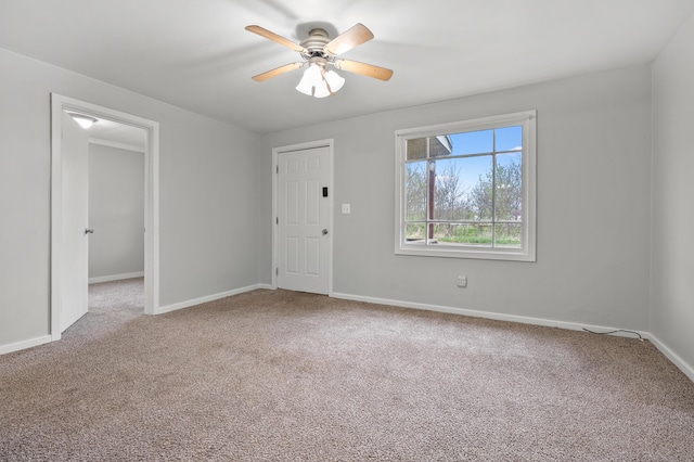 carpeted empty room featuring baseboards and ceiling fan