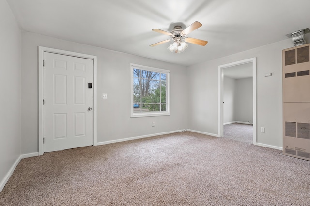 interior space with a heating unit, baseboards, a ceiling fan, and carpet floors