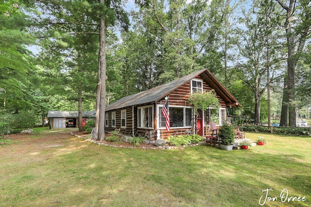view of front facade with a front yard, an outdoor structure, and a storage shed