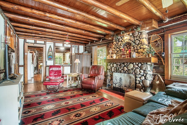living room with wooden ceiling, a stone fireplace, rustic walls, wood-type flooring, and beamed ceiling