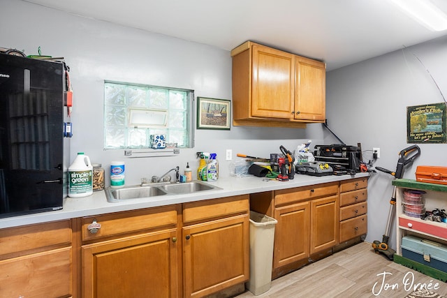 kitchen with a sink, brown cabinetry, light countertops, and light wood-type flooring