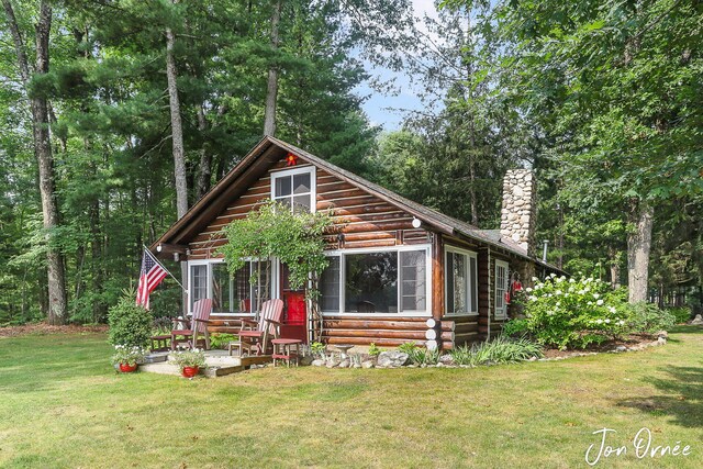 log home with a chimney, entry steps, a front lawn, and log exterior