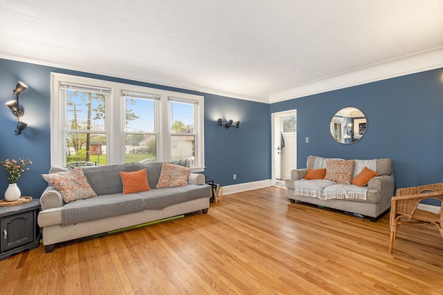 living area with light wood-style flooring, baseboards, and ornamental molding