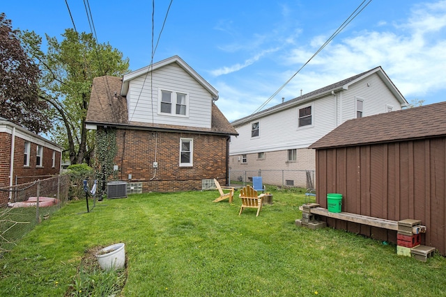 rear view of property featuring a storage unit, a lawn, an outdoor structure, a fenced backyard, and brick siding