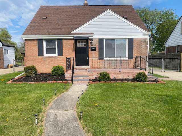 view of front of property featuring fence, brick siding, a front yard, a chimney, and a shingled roof