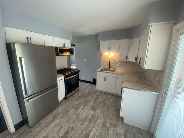 kitchen featuring white cabinetry, appliances with stainless steel finishes, tasteful backsplash, and light wood-style floors