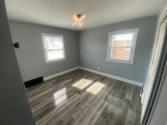unfurnished room featuring a wealth of natural light, ornamental molding, and dark wood-style floors