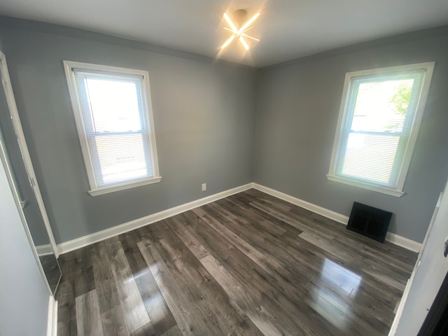 spare room featuring dark wood-style flooring, ornamental molding, baseboards, and visible vents