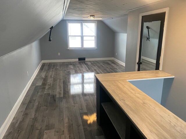 bonus room featuring a ceiling fan, baseboards, lofted ceiling, and dark wood-style floors