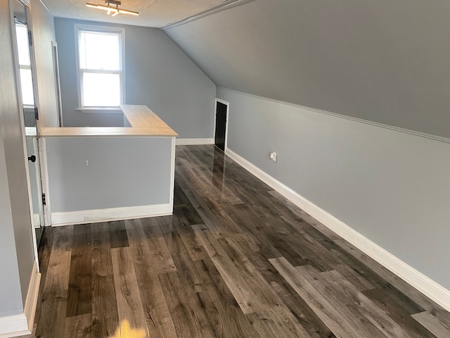 bonus room with baseboards, vaulted ceiling, and dark wood-type flooring