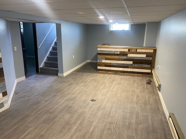 below grade area with wood finished floors, a baseboard radiator, and stairs