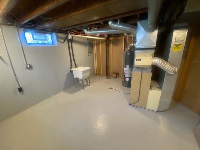 below grade area featuring water heater, a sink, and heating unit