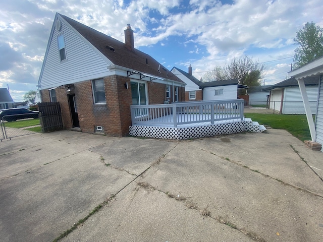 back of house with fence, a chimney, brick siding, and a deck