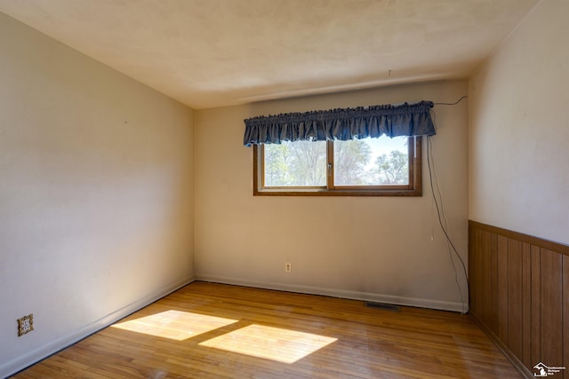empty room featuring baseboards, visible vents, and wood finished floors