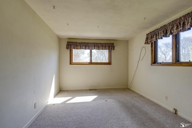 unfurnished room featuring carpet flooring, visible vents, and baseboards
