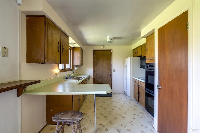 kitchen featuring brown cabinets, a sink, light floors, dobule oven black, and light countertops