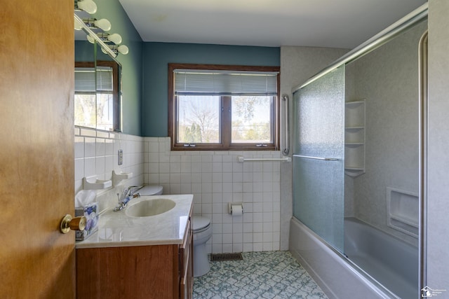 bathroom featuring vanity, toilet, tile walls, and a healthy amount of sunlight