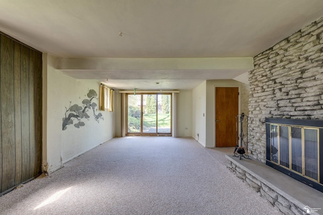 unfurnished living room with wood walls, a fireplace, and carpet floors