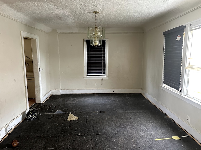 empty room featuring a textured ceiling, baseboards, and a notable chandelier