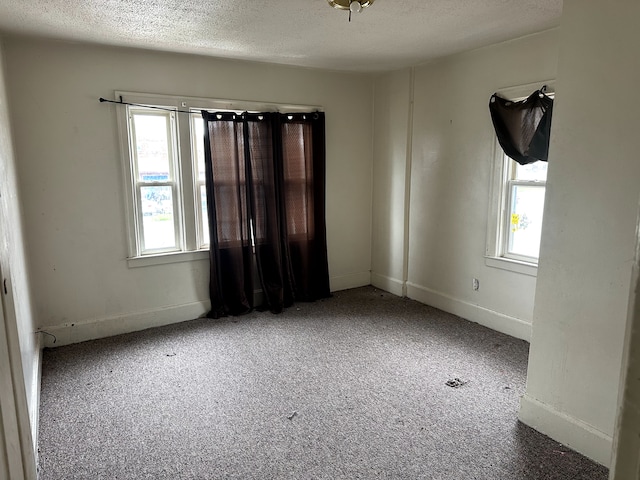 carpeted spare room featuring baseboards and a textured ceiling