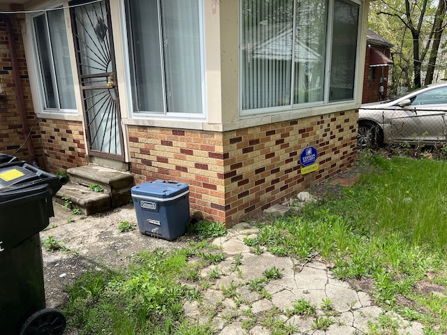 view of property exterior with entry steps, brick siding, and fence