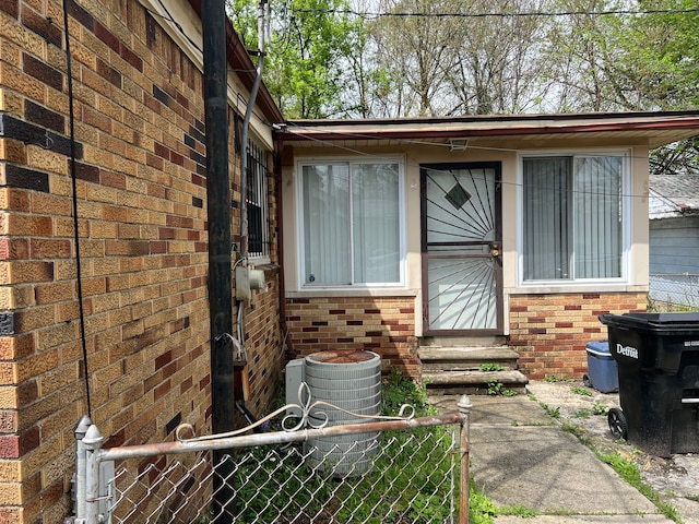property entrance with fence, brick siding, and a gate