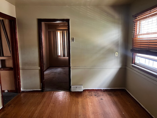 spare room with plenty of natural light, wood finished floors, and baseboards